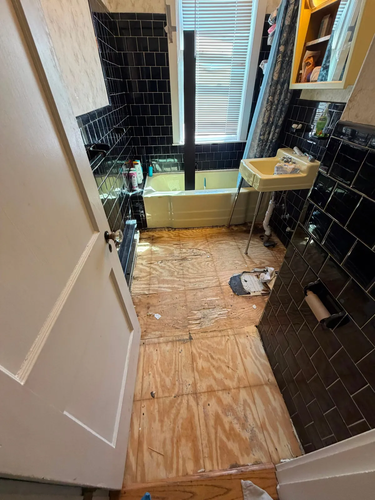 Bathroom stripped down to the plywood subfloor before new flooring