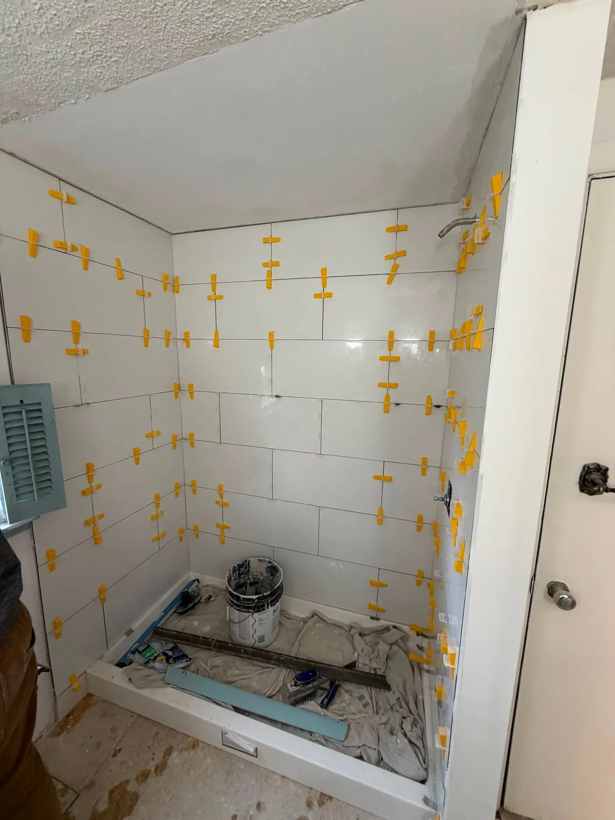 New shower tile being installed with leveling clips