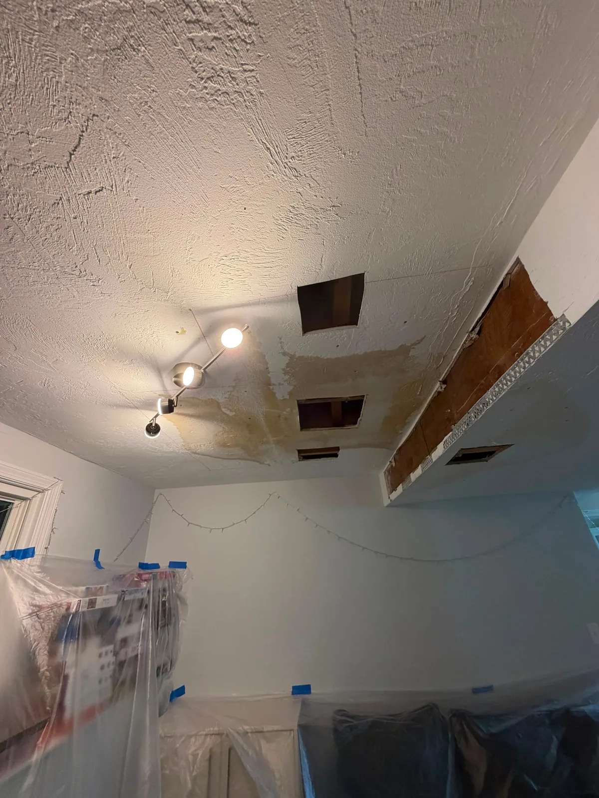 Damaged ceiling with holes and patches before repair