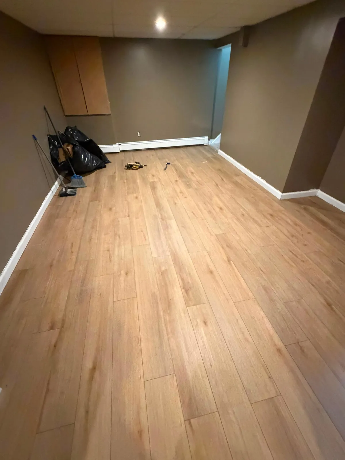 Basement family room with new light wood-look plank flooring installed